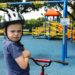 boy in blue denim vest and helmet riding red bicycle